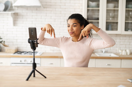 Backstage of young African American blogger streaming video online or recording tutorial for social media network, pointing with fingers in the air, showing subscribe to my channel, link bellow signsの写真素材