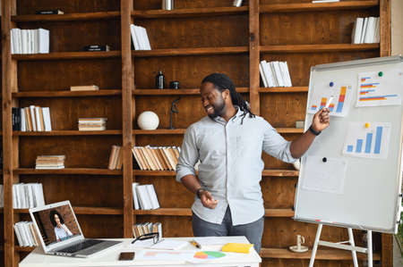 A smart and confident African male office employee sharing good results with a female colleague on...