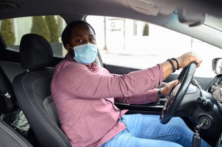 African American male taxi car driver wearing protective face mask or respirator for protection...