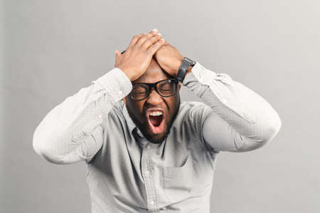 Frustrated African-American guy screaming no, stressful black holding man has panic attack, depression, a lot of problems have accumulated, studio shot isolated on greyの写真素材