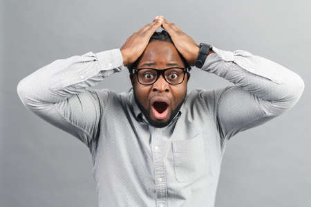 Portrait of forgetful young African American customer or employee wearing shirt looking with shocked...