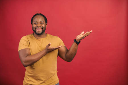 African American man standing isolated over red background pointing indicating with hands on the blank space for advertisement, mockup image, check this out, excited about new product or applicationの写真素材
