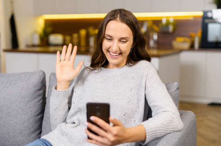 Video connection on the distance. Positive young woman using the smartphone for video call. Smiling...