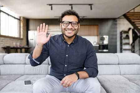 Video chat with indian male employee, mixed race colleague. Screen with a mixed-race guy on it, a...