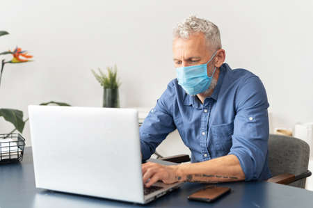 New reality and new rules for office staff during pandemic. Mature gray-haired male employee wearing...