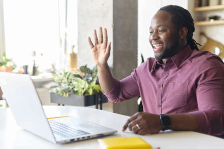 Stay in touch with work team during quarantine. African-American guy using laptop for video...