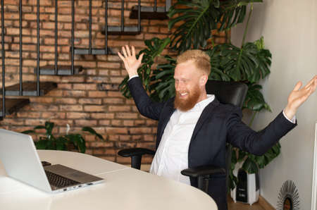 Happy male office employee in formal wear raising fists in triumph, celebrate good news, received unbelievable deal, businessman rejoice sitting in office and looking at laptop screen. Win and luckyの写真素材