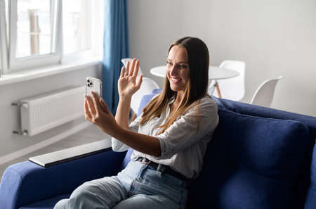 Young happy woman using mobile app on the smartphone for video connection, holding video chat on the...