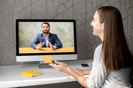 Young woman talking online with an Indian man, support service representative or colleague via video...