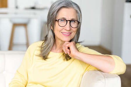Portrait of a charming mature lady posing and looking at the camera, gray-haired senior woman in...