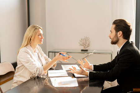 Young modern woman and man in smart casual wear chatting and working with each other in the office....