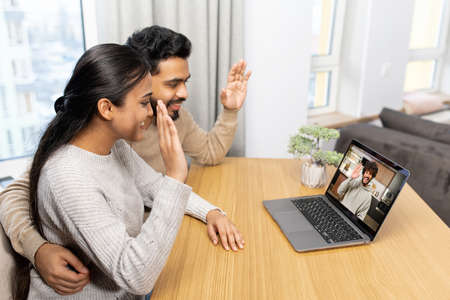 Interracial couple talking online, having video meeting on the laptop with family or friends....