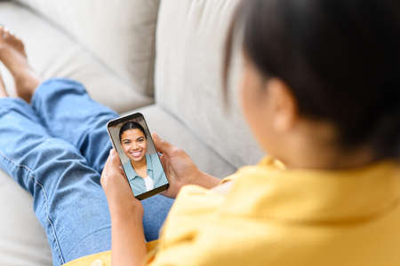 African-American woman using smartphone for video communication with female friend on the distance....