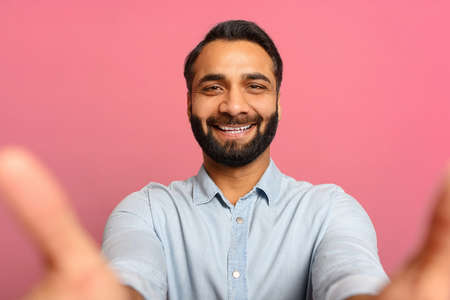 Portrait of bearded Indian handsome man taking selfie, looking at camera POV, multiracial...