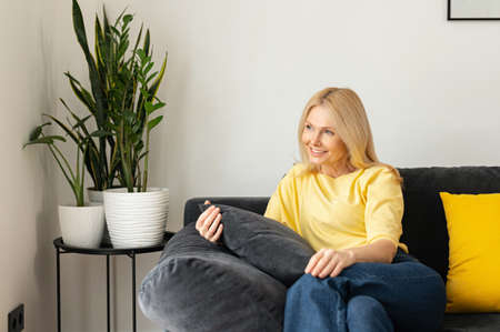 Enchanting carefree caucasian woman sitting on the couch and relaxing. Portrait of charming senior...