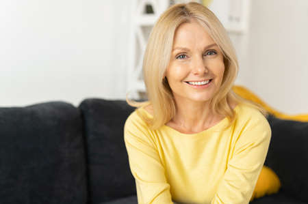 Senior woman in home interior. Charming mature caucasian lady looking at the camera and laughing,...
