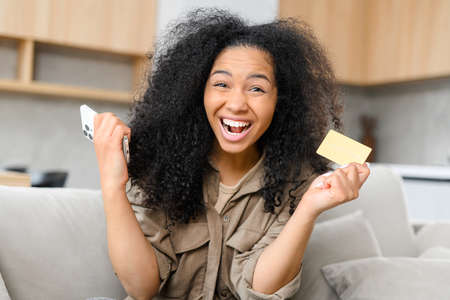 Overjoyed multiracial teenage woman dreaming about future purchase, spending money from the first...