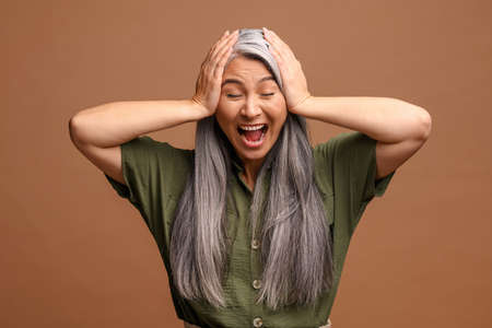 I do not want to hear anything. Mature irritated woman yelling with closed eye, studio shot isolated...