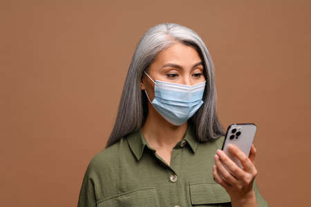 Protect yourself from epidemic, communicate remotely. A senior woman in a medical mask on her face...