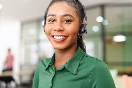 Headshot of young african-american female employee wearing wireless headset, looking at the camera...