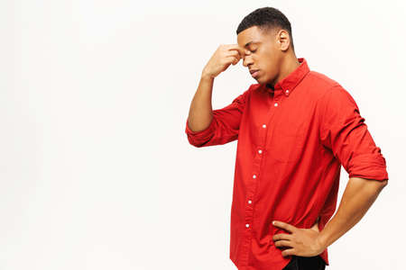 Problem, depression or sickness. Portrait of sad alone handsome young man in shirt standing, holding head down and crying. Indoor studio shot isolated on white backgroundの写真素材