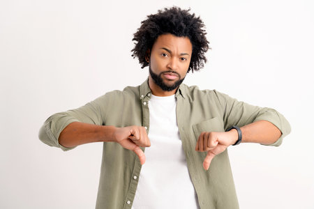 Upset unsatisfied man showing thumbs down with isolated on white background, african-american guy...