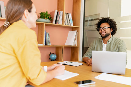 Man and woman looking each other while working laptop and standing in the modern office, coworkers...