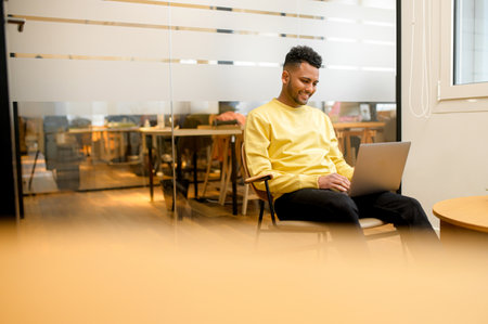 Concentrated determined young freelancer guy sitting in armchair in relaxed pose, typing on laptop, programmer is working on project, developing software, male student websurfingの写真素材