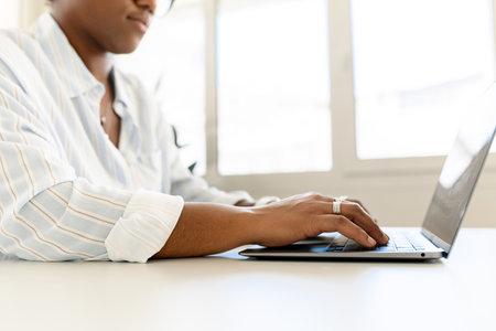 Cropped picture of african-american woman using laptop, female employee is typing on the keyboard,...