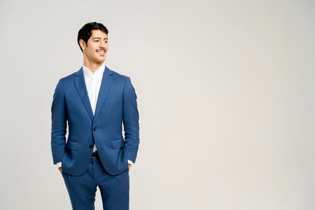 Young handsome male office employee dressed in a sharp blue suit standing with hands in pockets isolated on white, the ideal image of a successful young professional.の写真素材