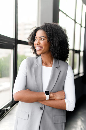 Businesswoman stands contemplatively by the window, arms crossed, looking out towards the city, then...