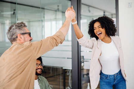 A high-five moment captures the joyful success within a team, as a woman beams with pride and a colleague applauds, showcasing a supportive and uplifting office culture. Value of team achievementsの写真素材