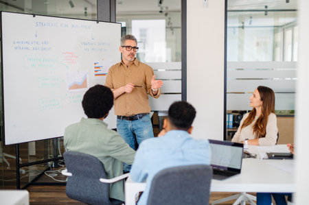Senior business leader delivering a strategic presentation to a diverse and engaged team. A modern corporate setting focused on business growth, teamwork, and leadership development.の写真素材