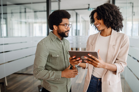 A business professional collaborating with a colleague on a digital tablet. A modern office environment fostering teamwork, productivity, and corporate success.の写真素材
