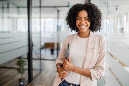 A confident and ambitious businesswoman smiling in a corporate office. A symbol of professional success, career growth, and leadership in a modern business environment.の写真素材