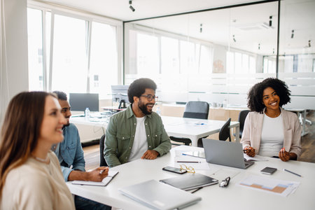 A business team enjoys a lighthearted moment during a meeting in a bright office. The diverse group fosters a collaborative and friendly work atmosphereの写真素材