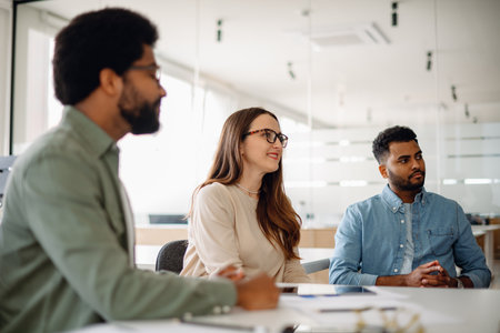 A diverse team of professionals engaged in a discussion in a modern office. Smiling colleagues collaborating on a project, brainstorming ideas, and sharing insights in a business environment.の写真素材