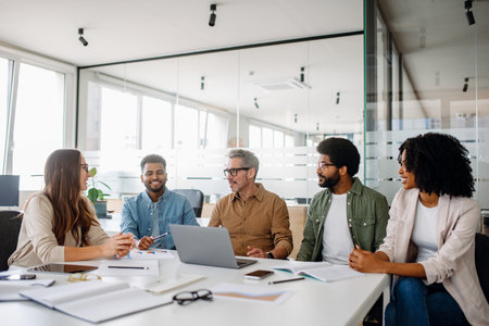 A diverse team engaged in a dynamic business discussion in a modern office. Collaboration and teamwork drive creativity and productivity. Ideal for business, leadership, and teamwork conceptsの写真素材