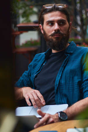 Top view of a freelancer workspace in a cafe. Smart phone, laptop, notepad, pencil, and coffee are on the table.の写真素材