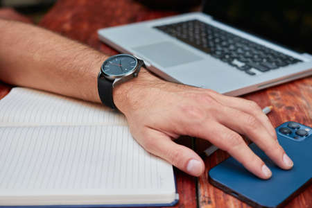 Top view of a freelancer workspace in a cafe. Smart phone, laptop, notepad, pencil, and coffee are...