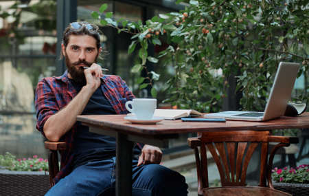 Top view of a freelancer workspace in a cafe. Smart phone, laptop, notepad, pencil, and coffee are on the table.の写真素材