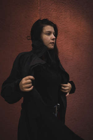 A girl in a black cloak on a red background.の写真素材