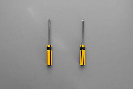 Cross and flat screwdrivers with yellow handle on a gray backgroundの写真素材