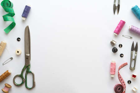 Flat lay composition with scissors and other sewing accessories on white background. Space for textの写真素材