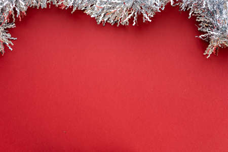 Christmas composition. Christmas decoration white tinsel on a red background. Flat lay, top view, space for textの写真素材