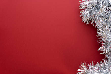 Christmas composition. Christmas decoration white tinsel on a red background. Flat lay, top view, space for textの写真素材