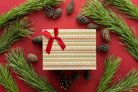 Christmas composition. A box with a gift and spruce branches on a red background. Spruce cones and Christmas decorations. Flat lay, top view, space for textの写真素材