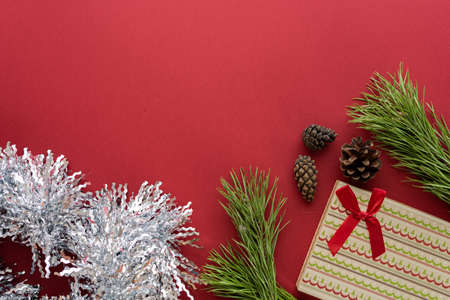 Christmas composition. A box with a gift and spruce branches on a red background. Spruce cones and Christmas decorations. Flat lay, top view, space for textの写真素材