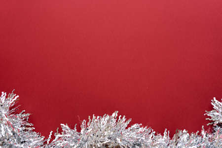 Christmas composition. Christmas decoration white tinsel on a red background. Flat lay, top view, space for textの写真素材
