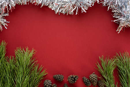 Christmas composition. Spruce branches and shishki with white tinsel on a red background. Flat lay, top view, space for textの写真素材